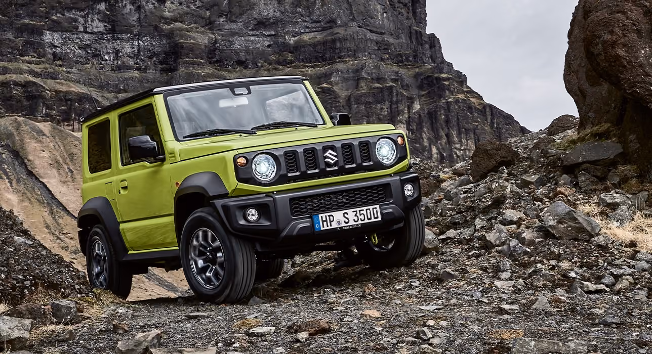 Abbildung zeigt einen grünen Jimny, der einen steinigen Hand hinauf fährt