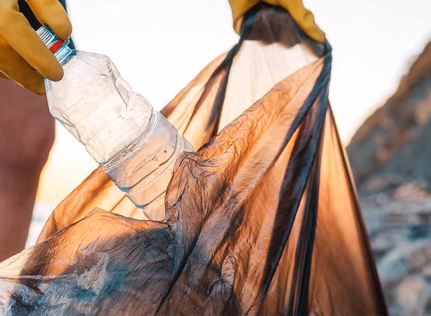 Plastikflasche wird in Müllsack gesteckt
